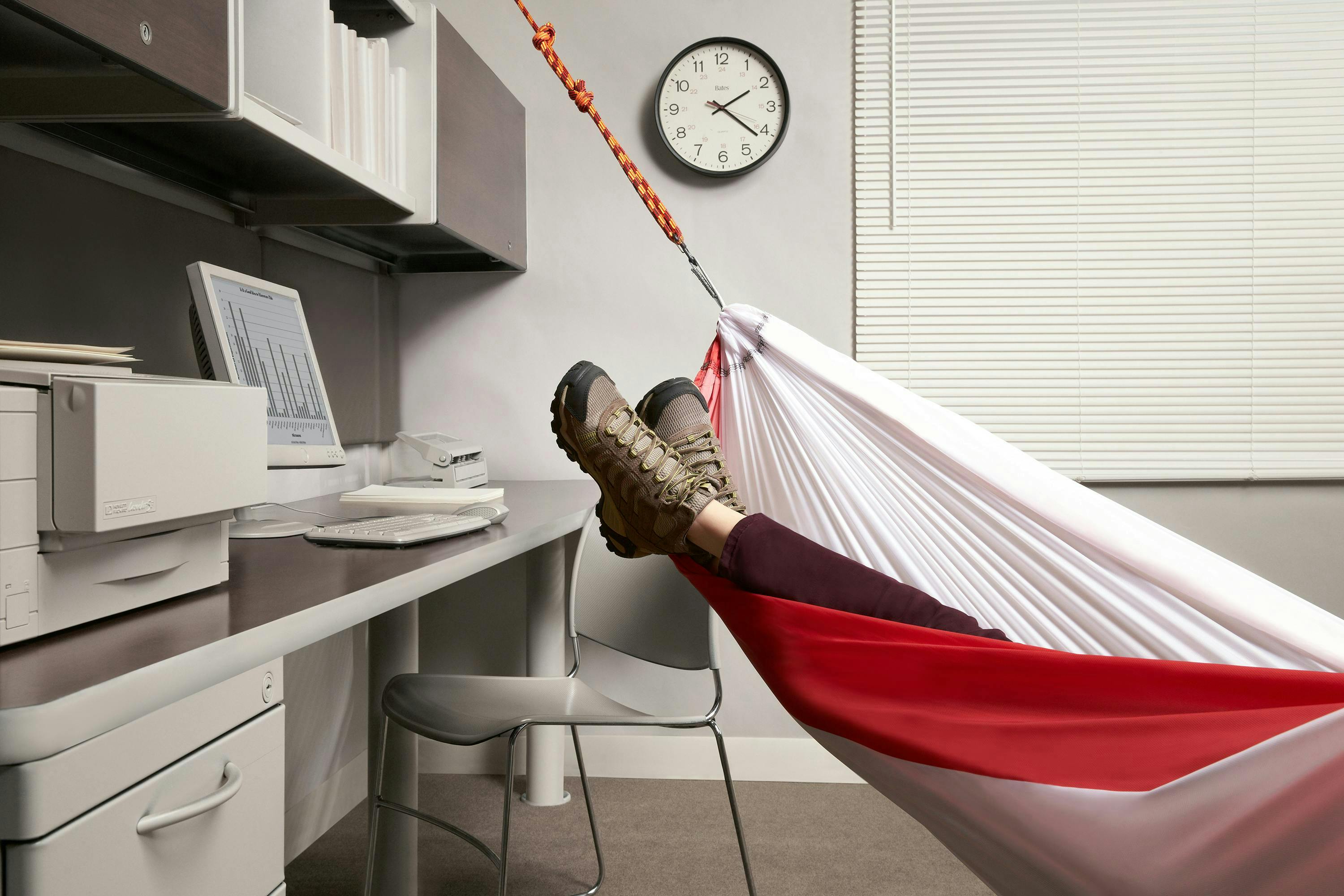 photoshoot with model wearing hiking boots in a hammock in a grey office space 