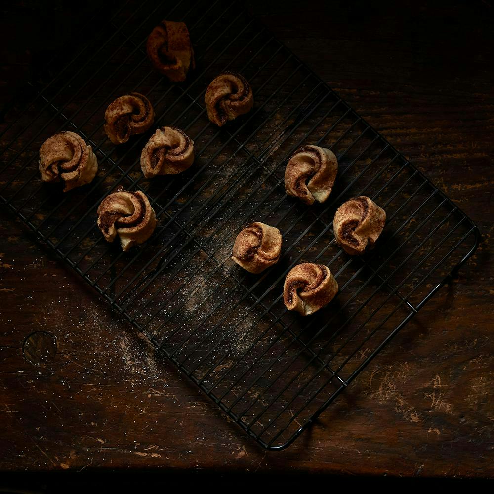 Flat lay product shot of cinnamon dough on a baking tray, on a wooden table. 