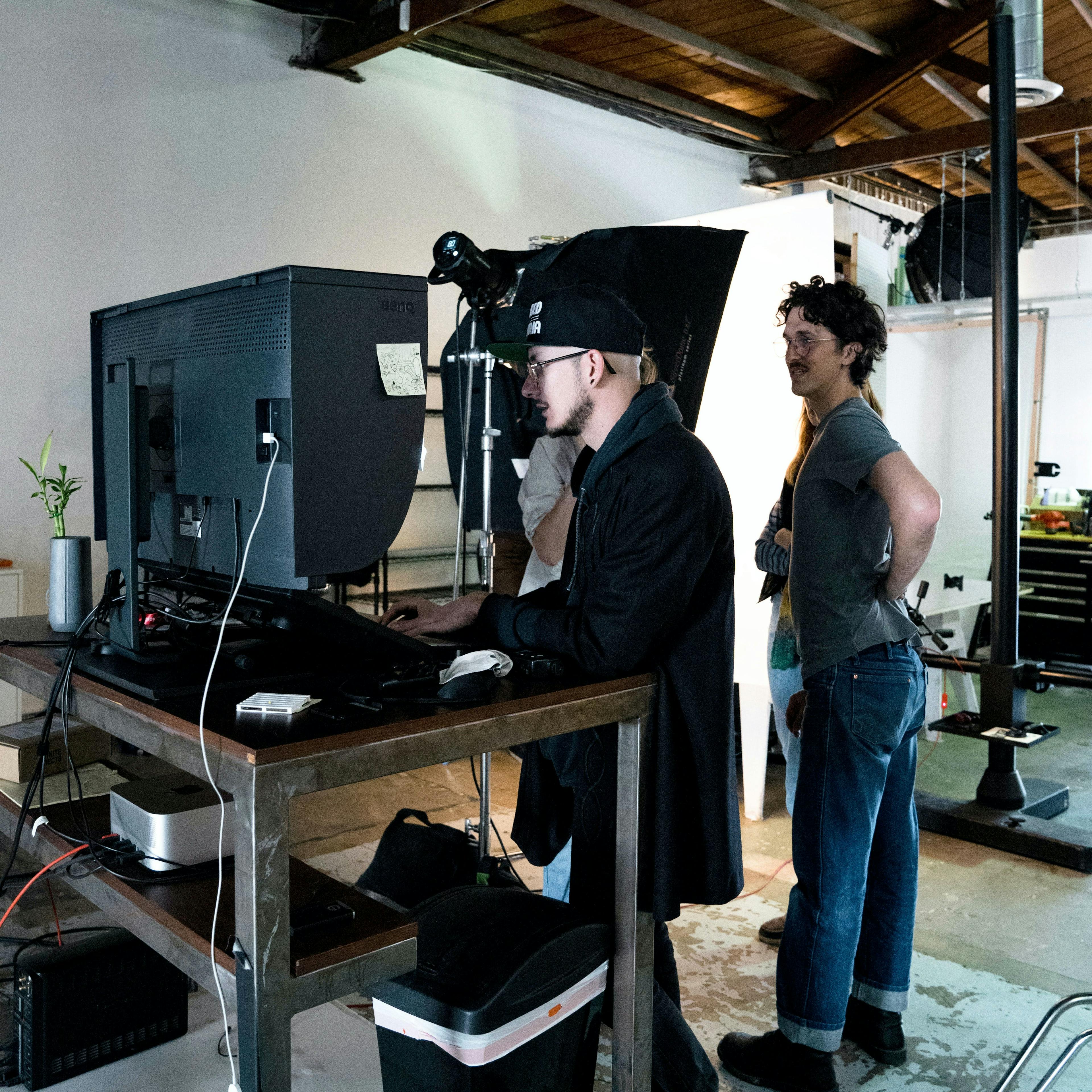 Photographer showing an image to a group of creative professionals standing around a computer, discussing the details of the shot