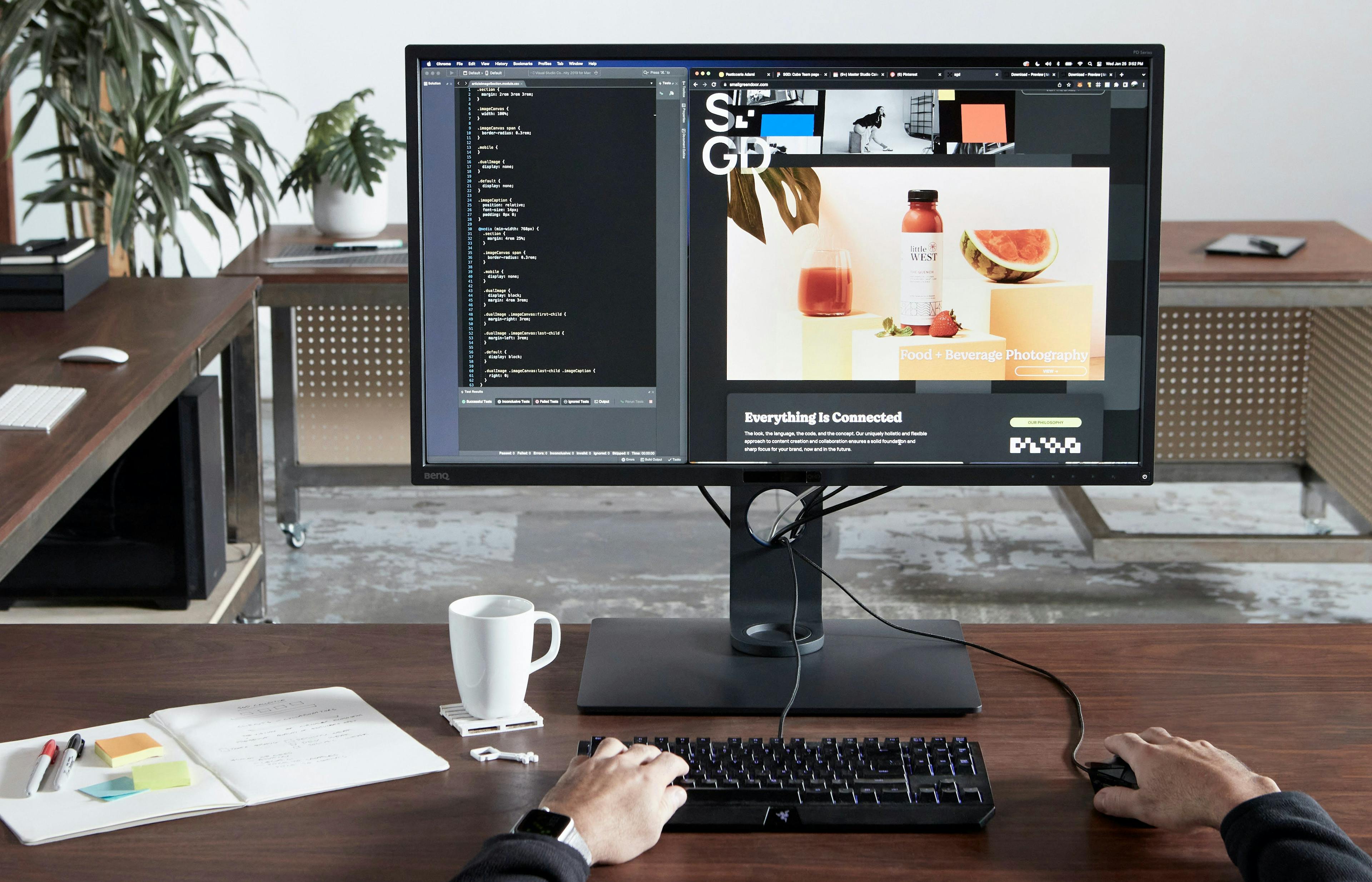 A programmer working on website development code on a desktop computer in a creative studio office.