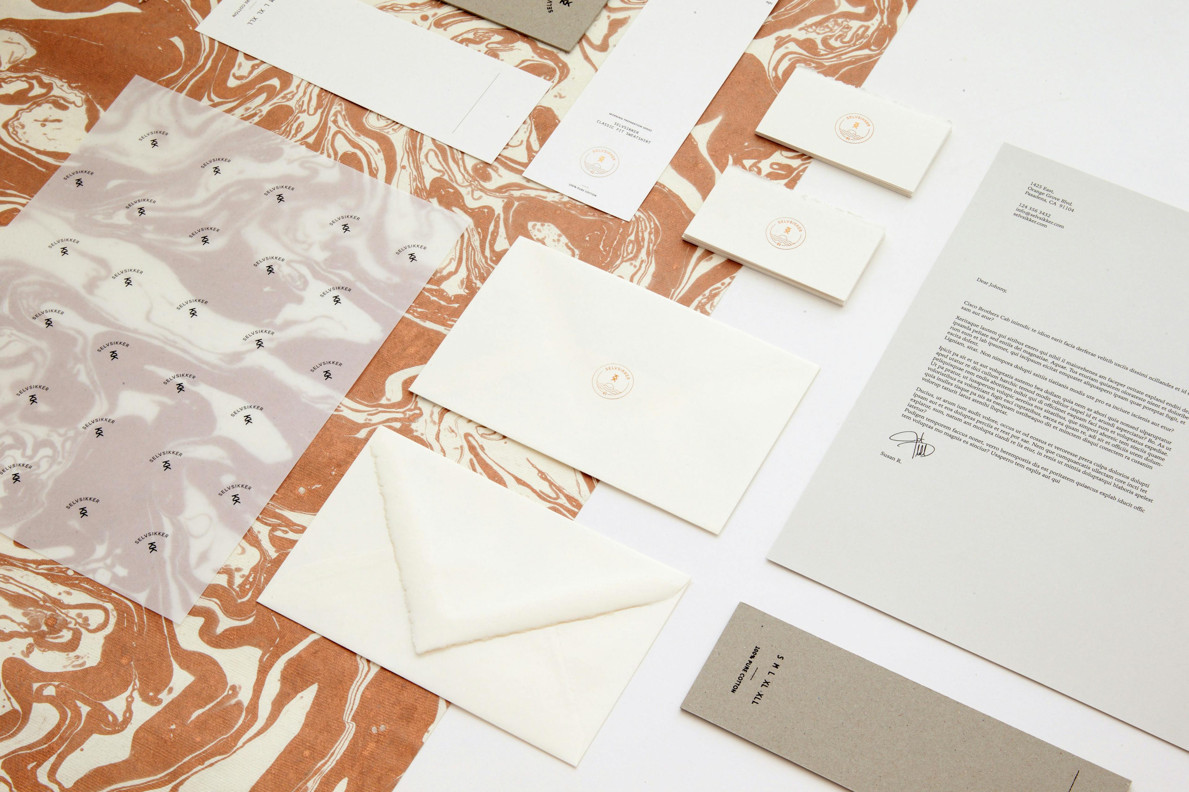 an image of print design process materials arranged in a grid pattern, including envelopes, stickers, and various paper materials.